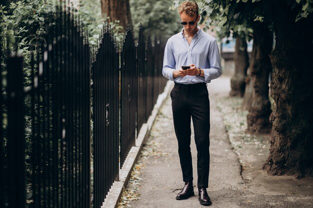 Jonge knappe man met behulp van telefoon in de straat