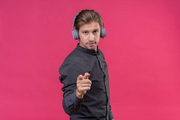 Jonge knappe man met koptelefoon met vinger naar voren