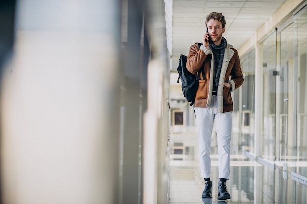 Jonge knappe man op de luchthaven praten aan de telefoon