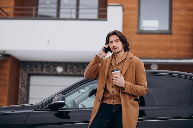 Jonge knappe man praten aan de telefoon door zijn auto