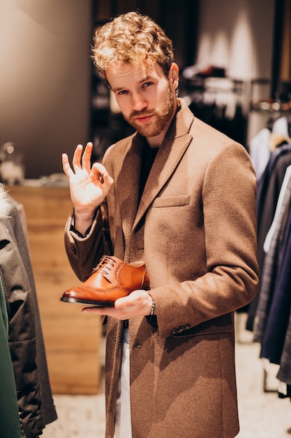 Gratis foto jonge knappe man schoenen kiezen in een winkel