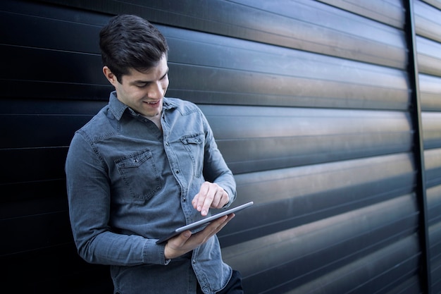 Jonge knappe man te typen op zijn tabletcomputer