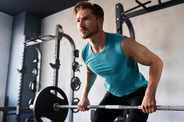 Jonge knappe man traint in de sportschool voor bodybuilding