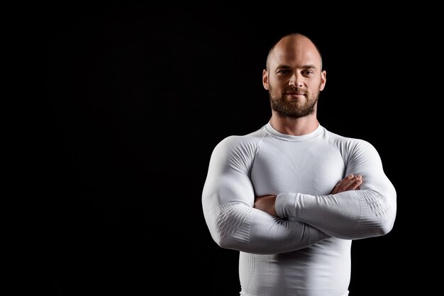 Jonge krachtige sportman in witte kleding over zwarte muur.