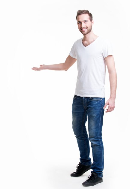 Jonge lachende man toont iets op arm - geïsoleerd op wit