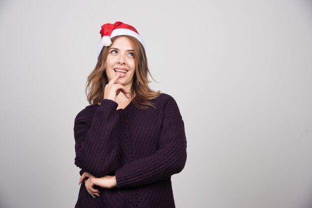 Jonge lachende vrouw in Santa's hoed staan en poseren.