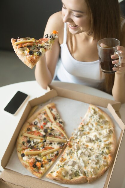 Jonge lachende vrouw met een stuk pizza
