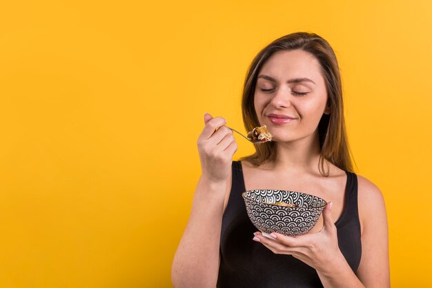 Jonge lachende vrouw met lepel en kom vlokken