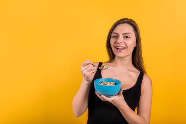 Jonge lachende vrouw met lepel en kom vlokken