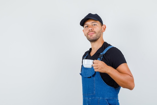 Jonge lader in uniform houden kopje turkse koffie, vooraanzicht.