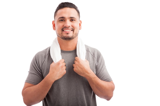 Jonge Latijns-atletische man met een handdoek om zijn nek die een pauze neemt van zijn training