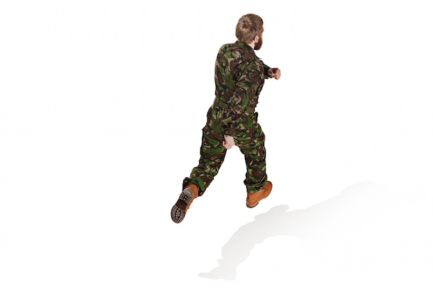 Jonge legermilitair die camouflage het eenvormige lopen dragen geïsoleerd op witte studio