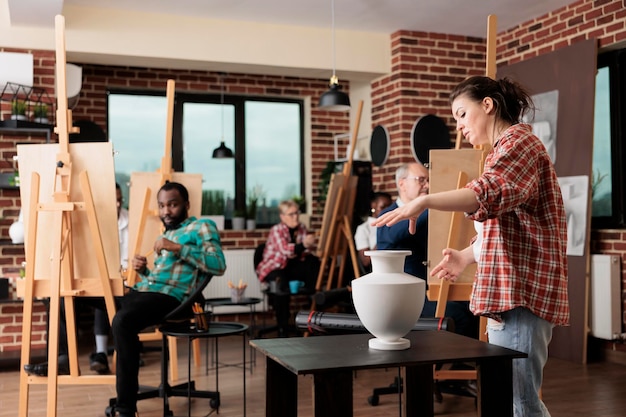 Gratis foto jonge lerares die tekenlessen geeft op een kunstacademie en mensen van verschillende leeftijden leert tekenen. groep diverse studenten die schetstechnieken leren. creatieve activiteiten voor volwassenen