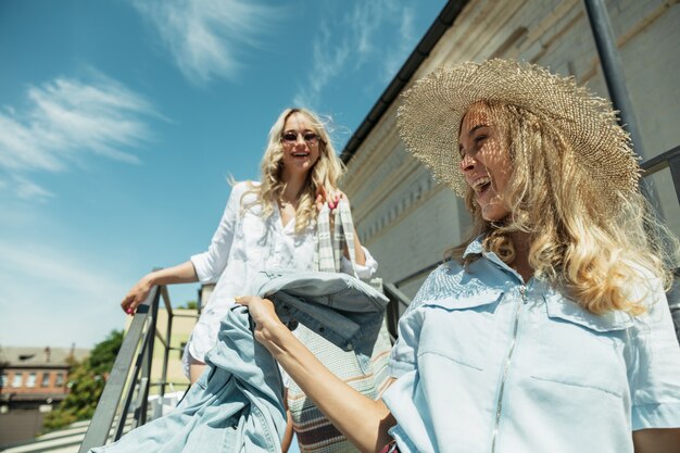 Jonge lesbische paar vakantie reis op de auto in zonnige dag voorbereiden. Lachende en gelukkige meisjes voordat ze naar zee of oceaan gaan. Concept van relatie, liefde, zomer, weekend, huwelijksreis, vakantie.