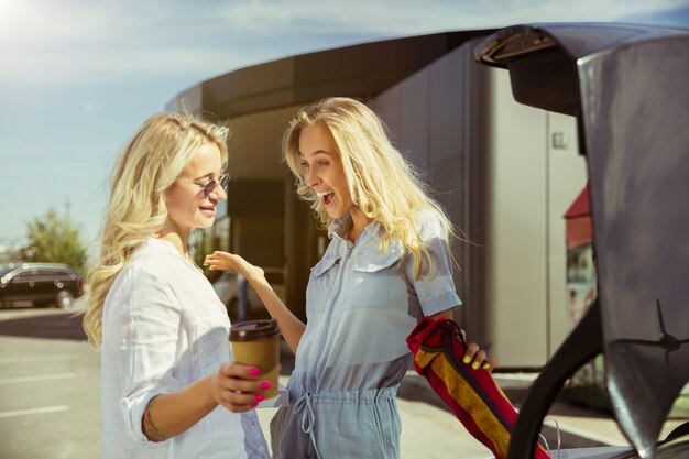 Jonge lesbische paar vakantie reis op de auto in zonnige dag voorbereiden. Winkelen en koffie drinken voordat je naar zee of oceaan gaat. Concept van relatie, liefde, zomer, weekend, huwelijksreis.