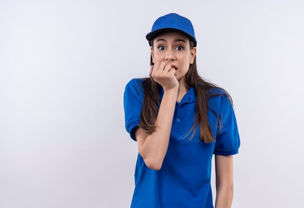 Jonge levering meisje in blauw uniform en pet gestrest en nerveus nagels bijten