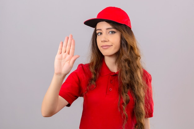 Jonge leveringsvrouw die rood poloshirt en GLB draagt die zich met open hand bevindt die stopbord doet met ernstig en zelfverzekerd uitdrukkingdefensiegebaar over geïsoleerde witte achtergrond