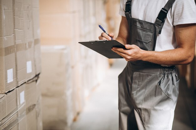 Jonge man aan het werk in een magazijn met dozen