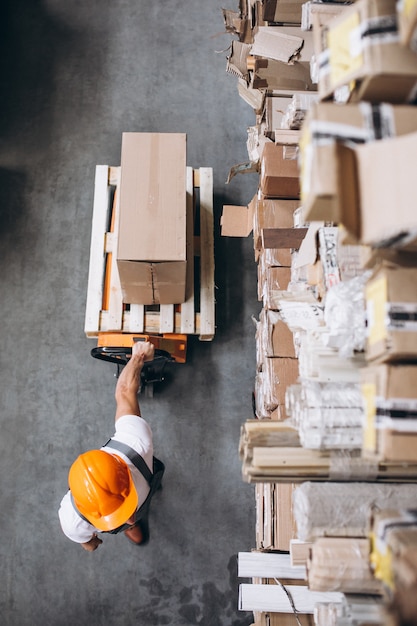 Gratis foto jonge man aan het werk in een magazijn met dozen