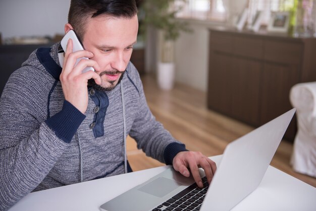 Jonge man aan het werk met zijn laptop thuis