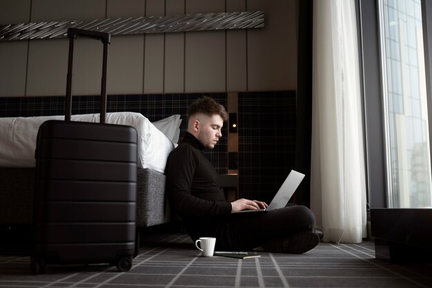 Jonge man aan het werk op zijn laptop in een hotelkamer