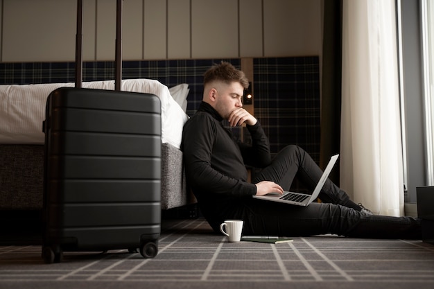 Gratis foto jonge man aan het werk op zijn laptop in een hotelkamer