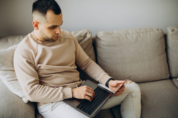 Jonge man aan het werk vanuit huis op laptop