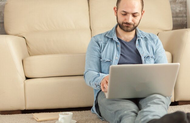 Jonge man aan het werk vanuit huis op laptop