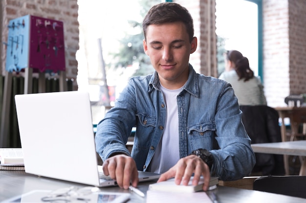 Gratis foto jonge man aan tafel met laptop