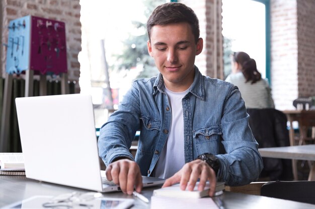 Jonge man aan tafel met laptop