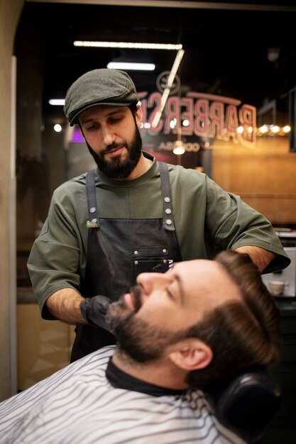 Jonge man bij de kapper die zijn baard laat trimmen