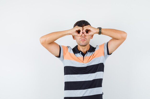 Jonge man bril gebaar in t-shirt tonen en waakzaam kijken