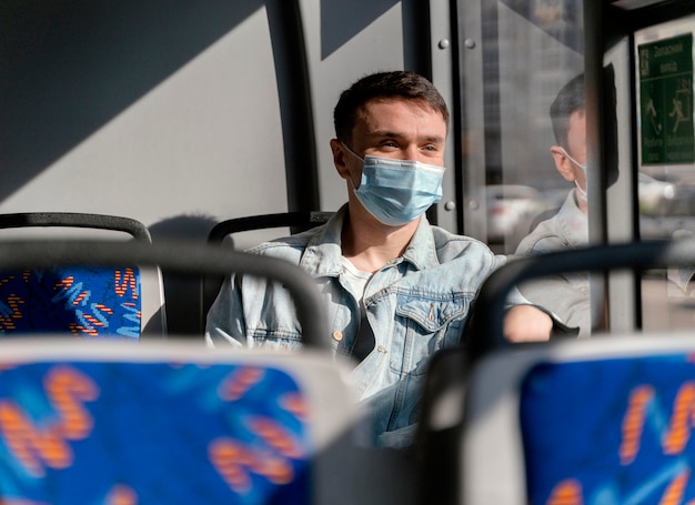 Jonge man die door stadsbus reist die chirurgisch masker draagt