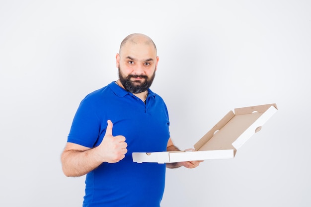 Jonge man die duim in t-shirt laat zien en er vrolijk uitziet. vooraanzicht.