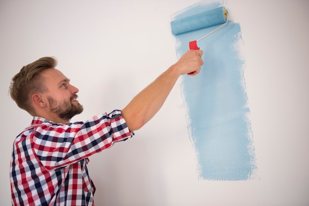 Jonge man die een blauwe muur schildert