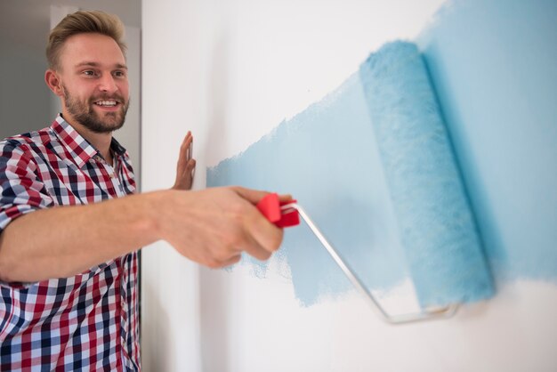 Jonge man die een blauwe muur schildert