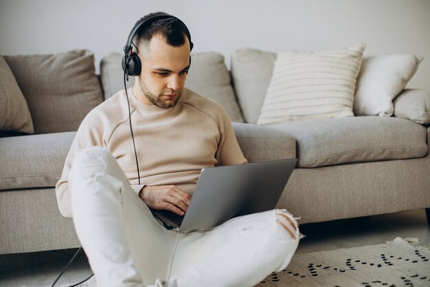 Jonge man die een koptelefoon draagt en thuis een computer gebruikt