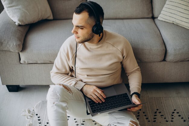 Jonge man die een koptelefoon draagt en thuis een computer gebruikt