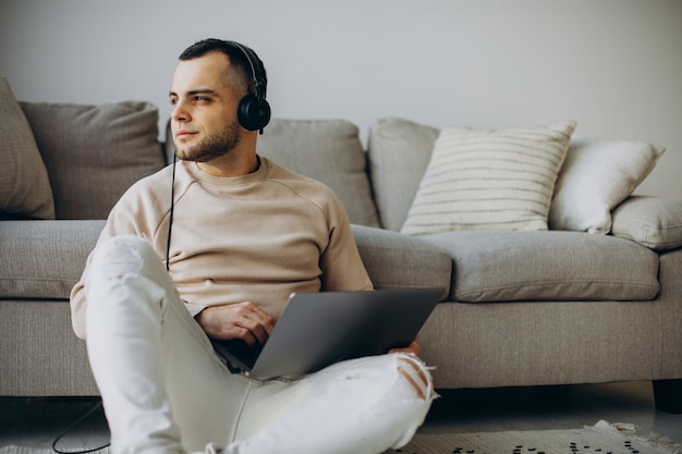 Jonge man die een koptelefoon draagt en thuis een computer gebruikt