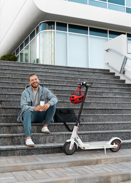 Gratis foto jonge man die een pauze neemt na het rijden op zijn scooter