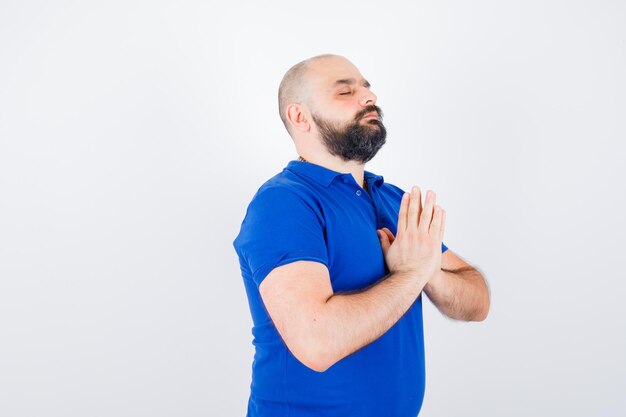 Jonge man die in blauw shirt wenst en er kalm uitziet. vooraanzicht.