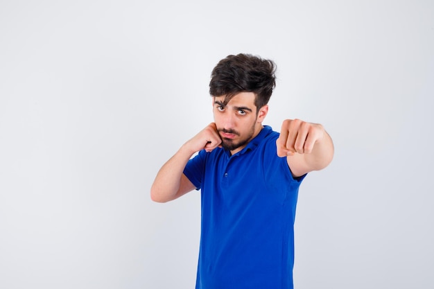 Jonge man die in een bokser staat in een blauw t-shirt en er serieus uitziet