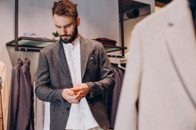 Jonge man die kleding kiest in herenkledingwinkel