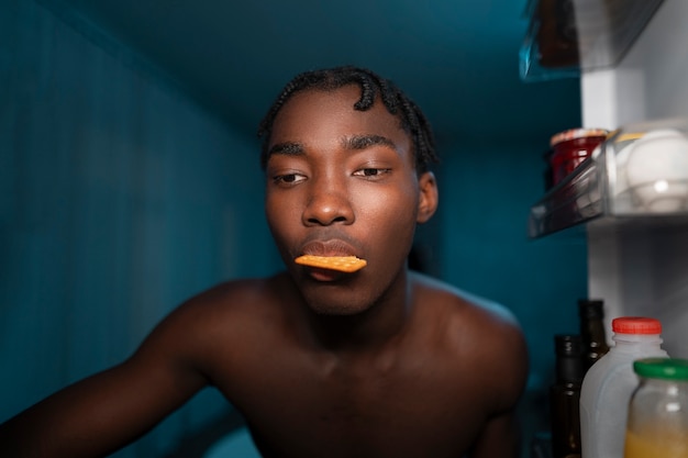 Gratis foto jonge man die midden in de nacht de koelkast thuis opent voor een snack