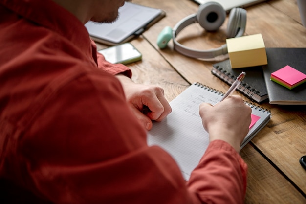 Gratis foto jonge man die op een notitieboekje schrijft tijdens studiesessie