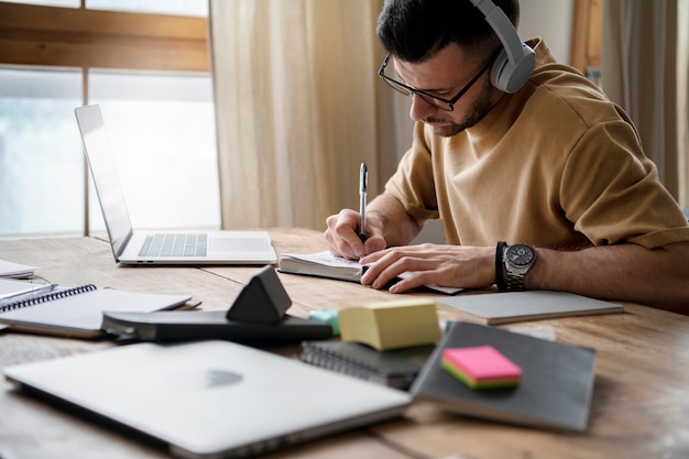 Jonge man die op een notitieboekje schrijft tijdens studiesessie