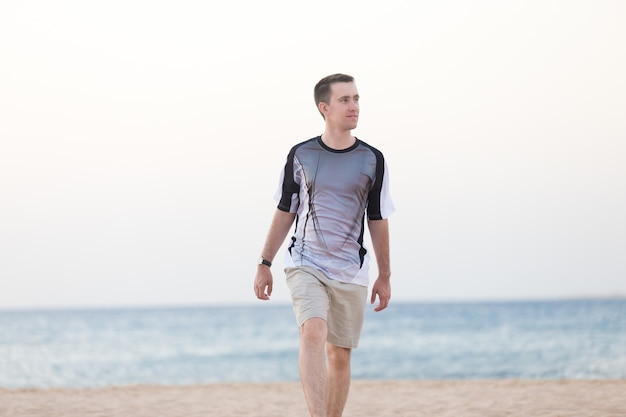 Jonge man die op het strand loopt