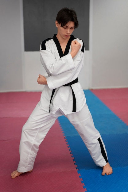 Gratis foto jonge man die taekwondo beoefent in een gymnasium