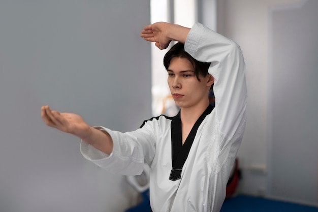 Gratis foto jonge man die taekwondo beoefent in een gymnasium