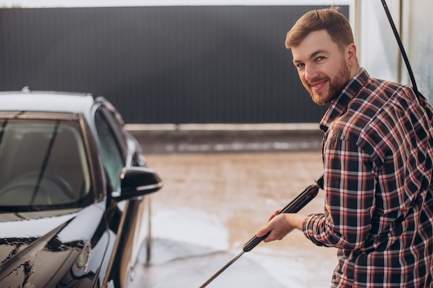 Jonge man die zijn auto wast bij carwash